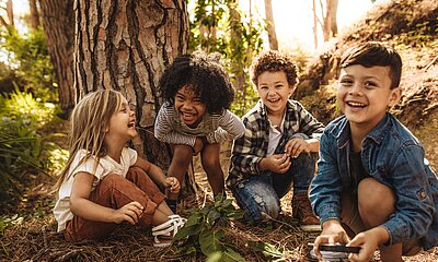 Vier Kinder lachen gemeinsam im Wald