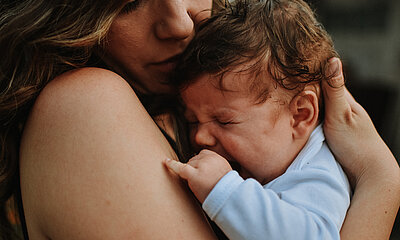 Baby weint in den Armen seiner Mutter