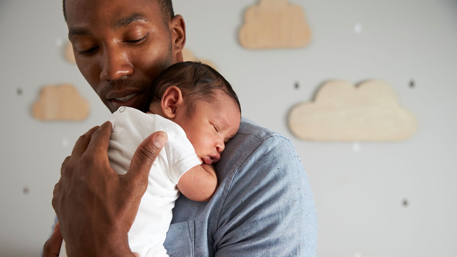 Vater hält sein schlafendes Neugeborenes im Arm