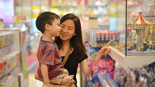 Mutter und ihr Sohn sind Spielzeug im Einkaufszentrum kaufen