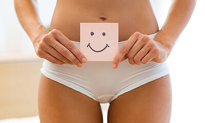 Eine Frau hält einen Post-IT Zettel mit einem Smiley for den Bauch