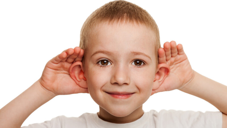 Junge hält sich beide Hände hinter die Ohren um besser zu hören