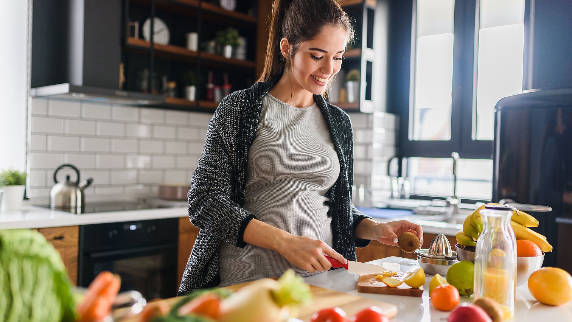 Schwangere Frau kocht in der Küche mit Gemüse