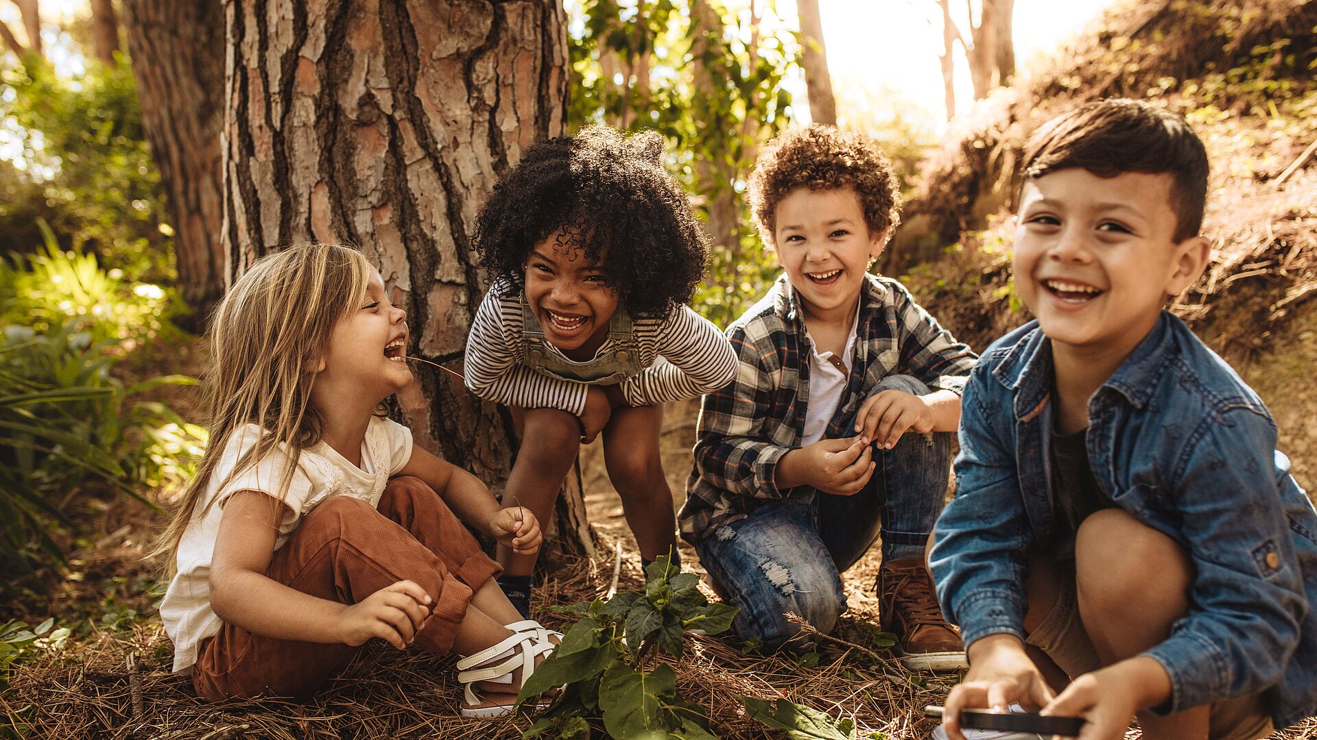 Vier Kinder lachen gemeinsam im Wald