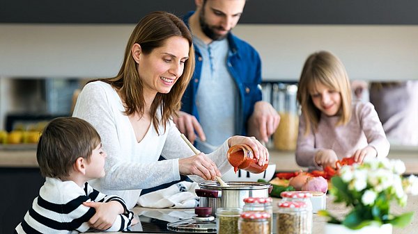 Mutter, Vater und deren zwei Kinder kochen gemeinsam. 