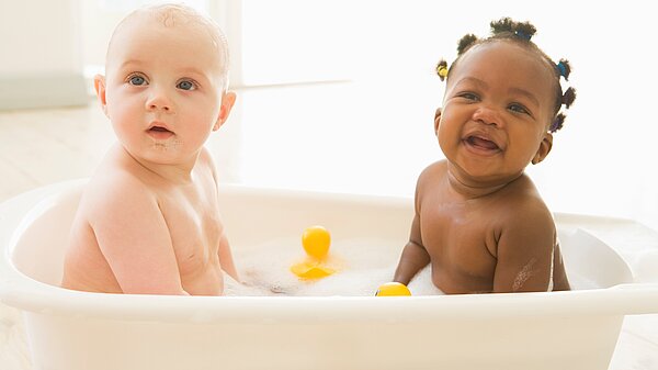 Zwei Babys sitzen zusammen in der Badewanne