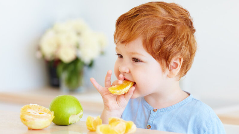 Kind beisst in Stücke einer Orange