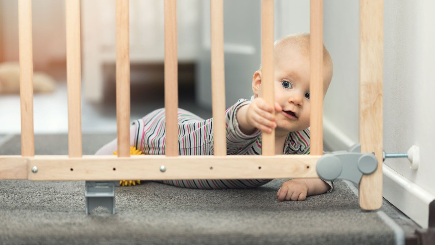 Baby liegt hinter Treppenschutzgitter