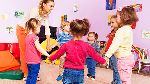 Eine Gruppe Kinder mit Kindergartenfachkraft