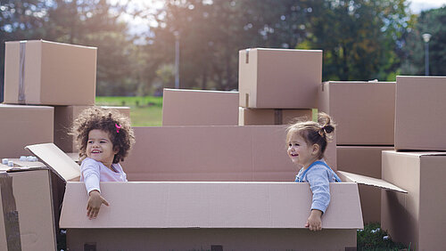 Zwei Kinder spielen zusammen in Pappkartons