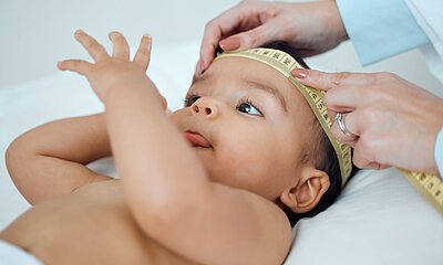 Baby mit Messband um den Kopf