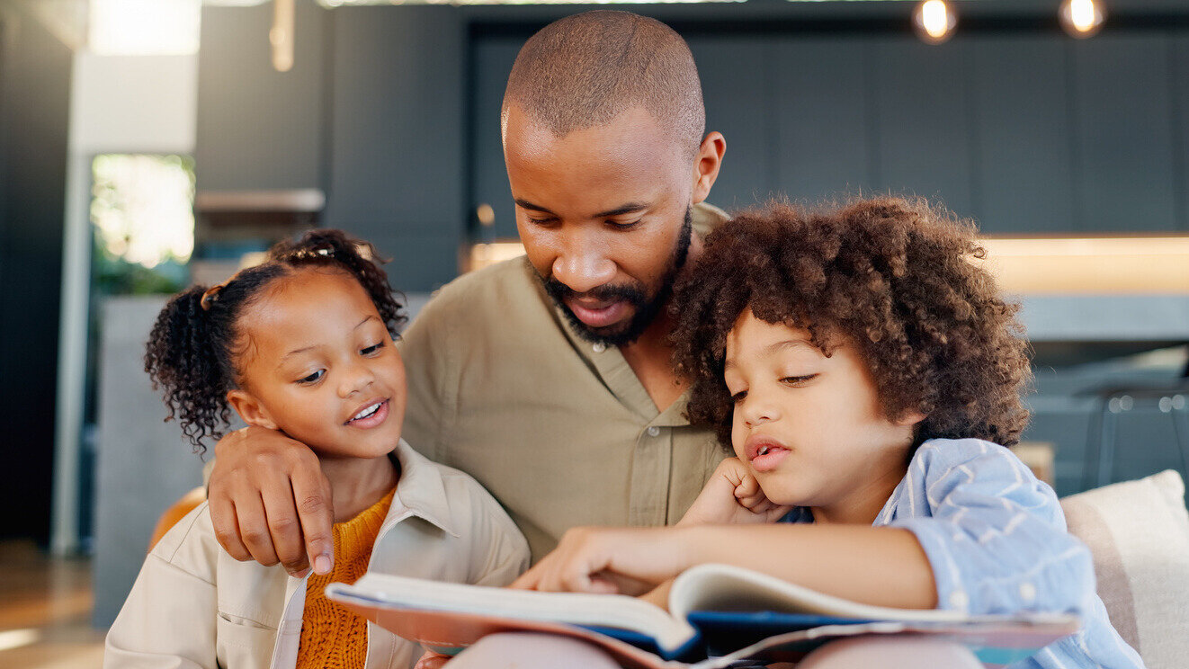 Vater und Kinder schauen interessiert in ein Buch